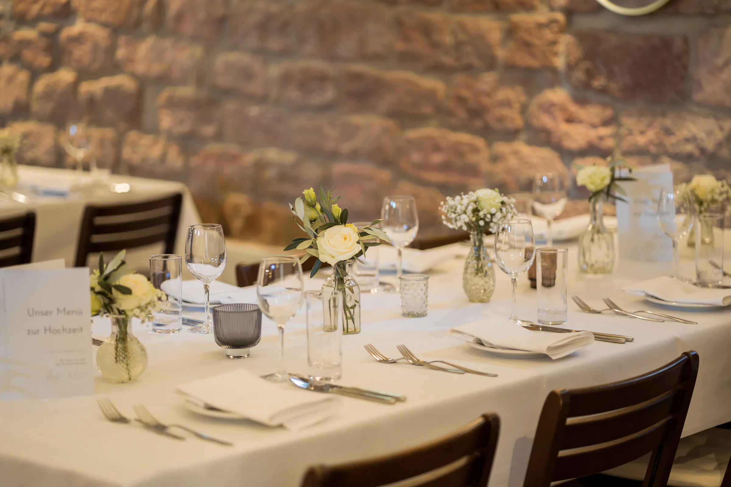 Tischdekoration mit weißen Rosen im Gewölbestall des Hofgut Habitzheim