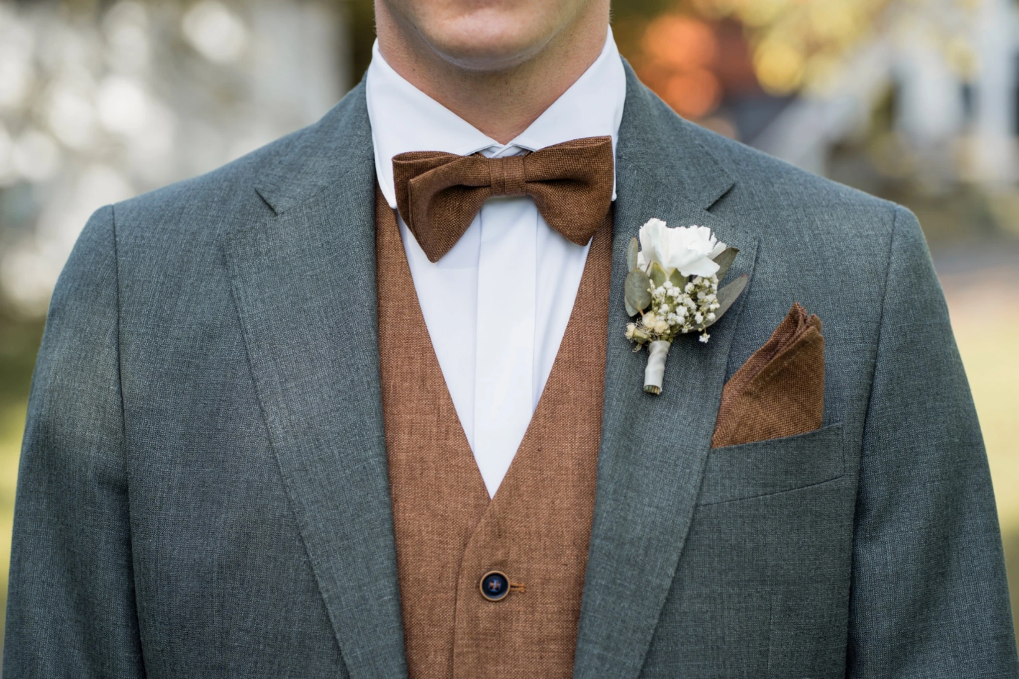 Reduziertes Detail des Bräutigam-Outfits mit Fliege und Ansteckblume vor der Trauung